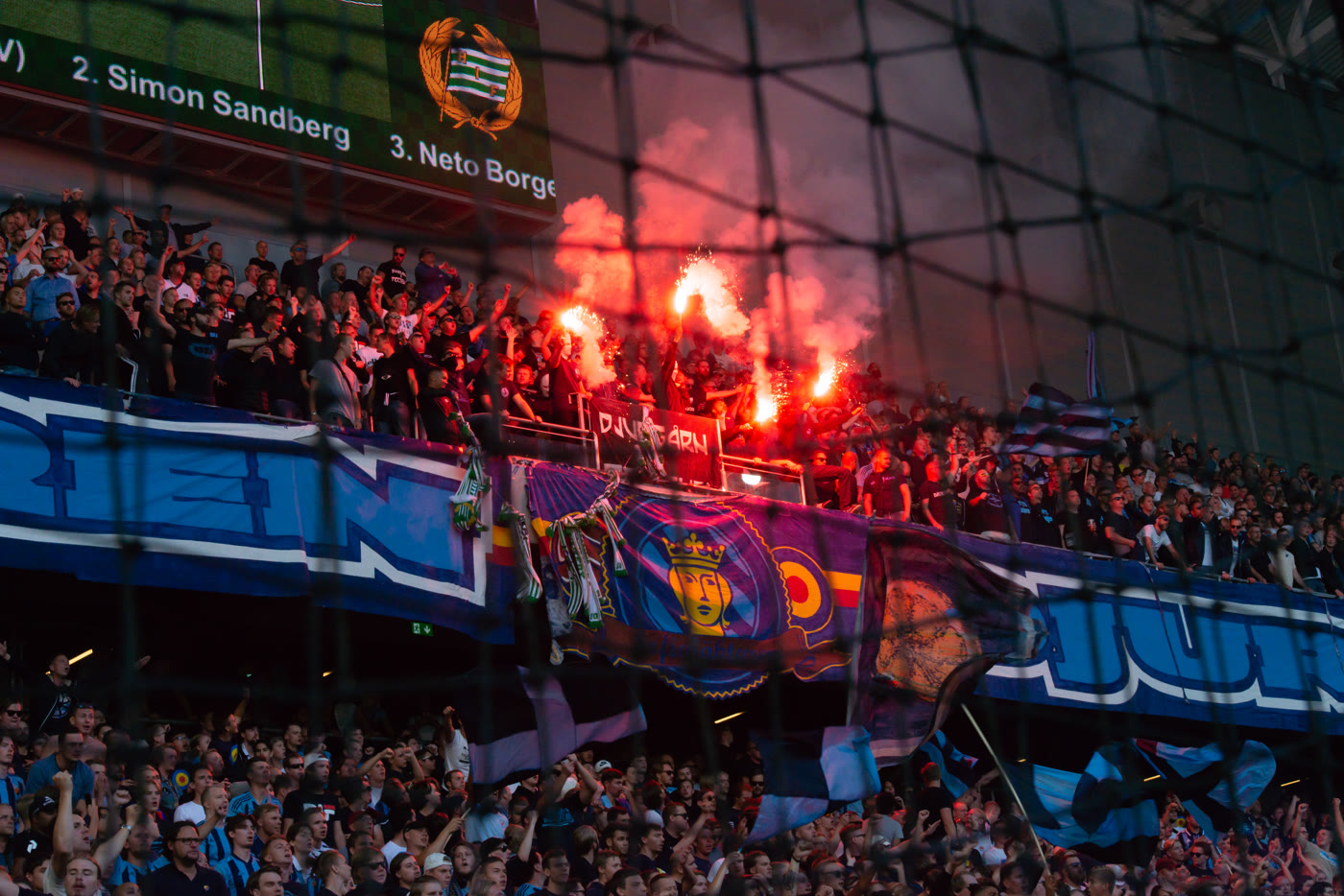 Zbijena masa navijača s upaljenom bakljom na fudbalskoj utakmici.